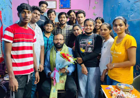 Vijay sir seated with a bouquet and a shawl, with his students standing around him