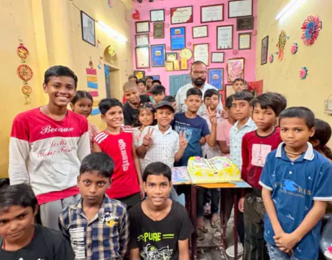 Young students of Vijay Classes around a cake, with Vijay sir standing behind them
