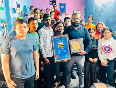 Vijay Kishor Tiwari holding his Incredible Teacher certificate and plaque, surrounded by his students at the centre